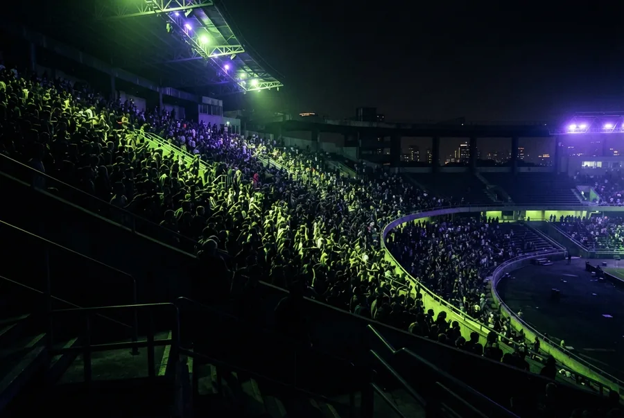 Illustration: Tribüne voller Silhouetten im Neonlicht — die Community